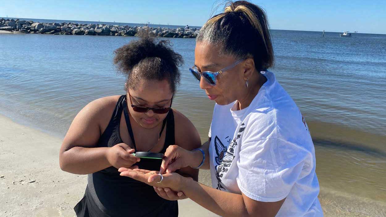 Sea Stars camper examines animal found at beach under magnifying glass