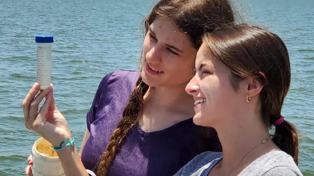 Students checking samples in a vial in the field